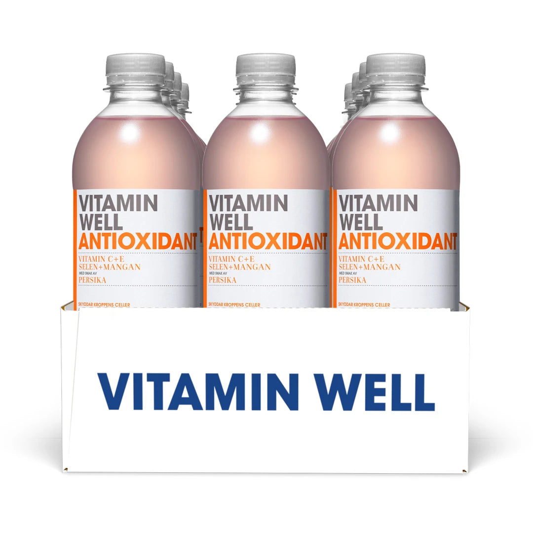 12 x Vitamin Well 500 ml Antioxidant Persika i ett vitt flak med genomskinliga plastflaskor och ljusrosa dryck.