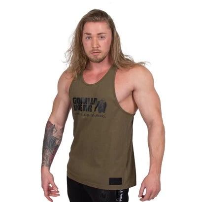 En man bär Gorilla Wear Classic Tank Top Army Green, ett löst brottarlinne i mjuk bomull med svart logotyp., bild 1 av 5