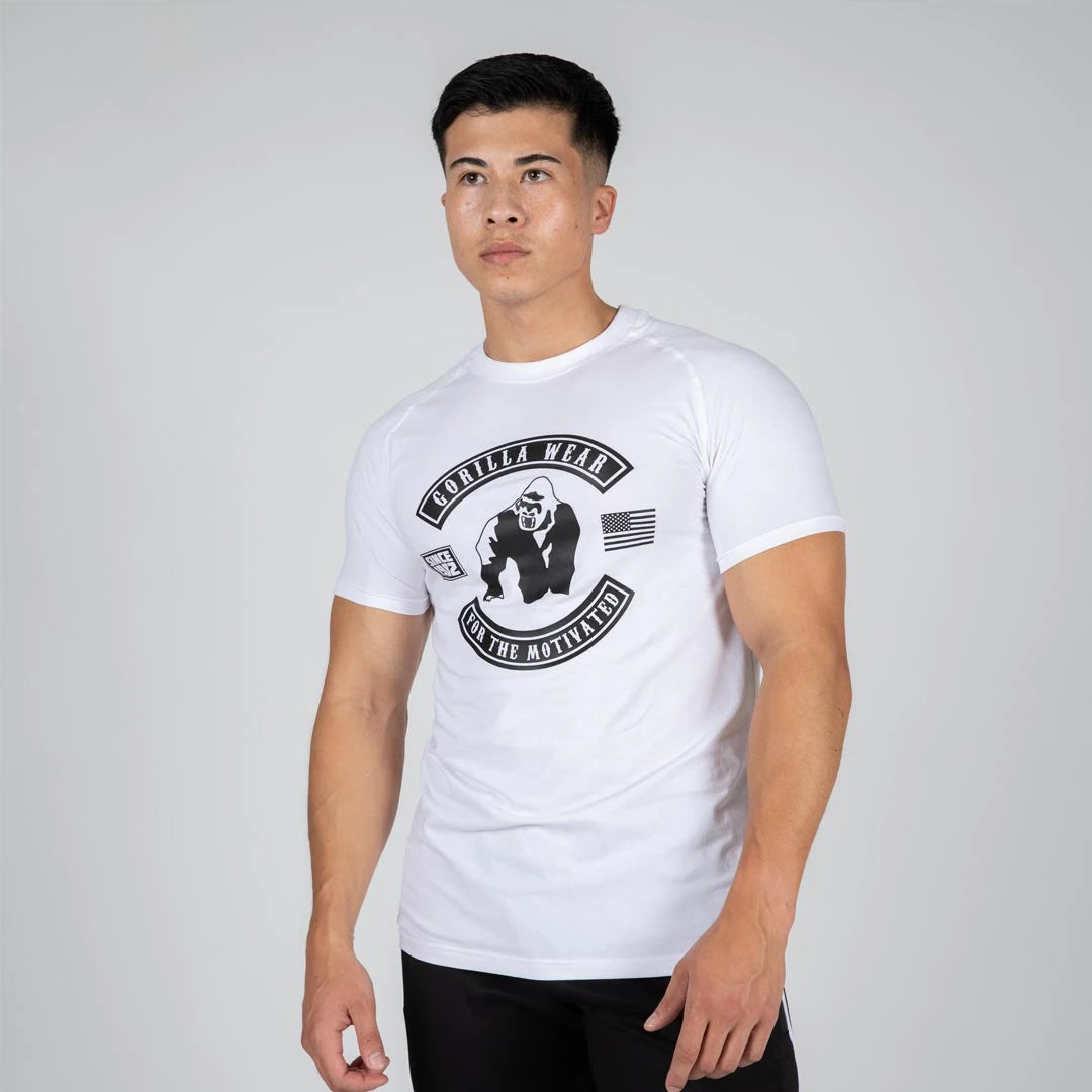 Man i Gorilla Wear Tulsa T-Shirt White, en vit kroppsnära tränings-t-shirt med stort svart logotryck.