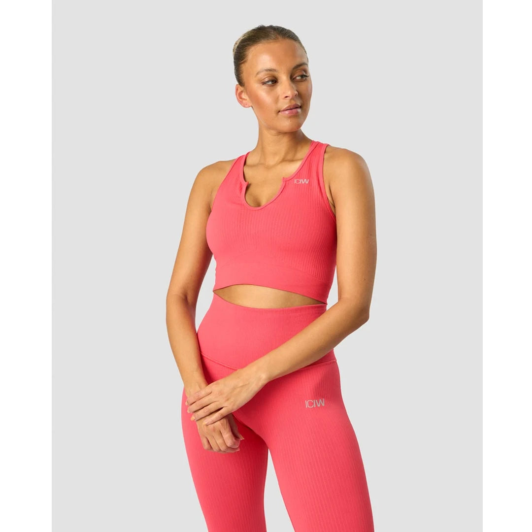 ICANIWILL Ribbed Define Seamless Tank Top Coral Red är ett korallrött, ribbat träningslinne buret av en modell.