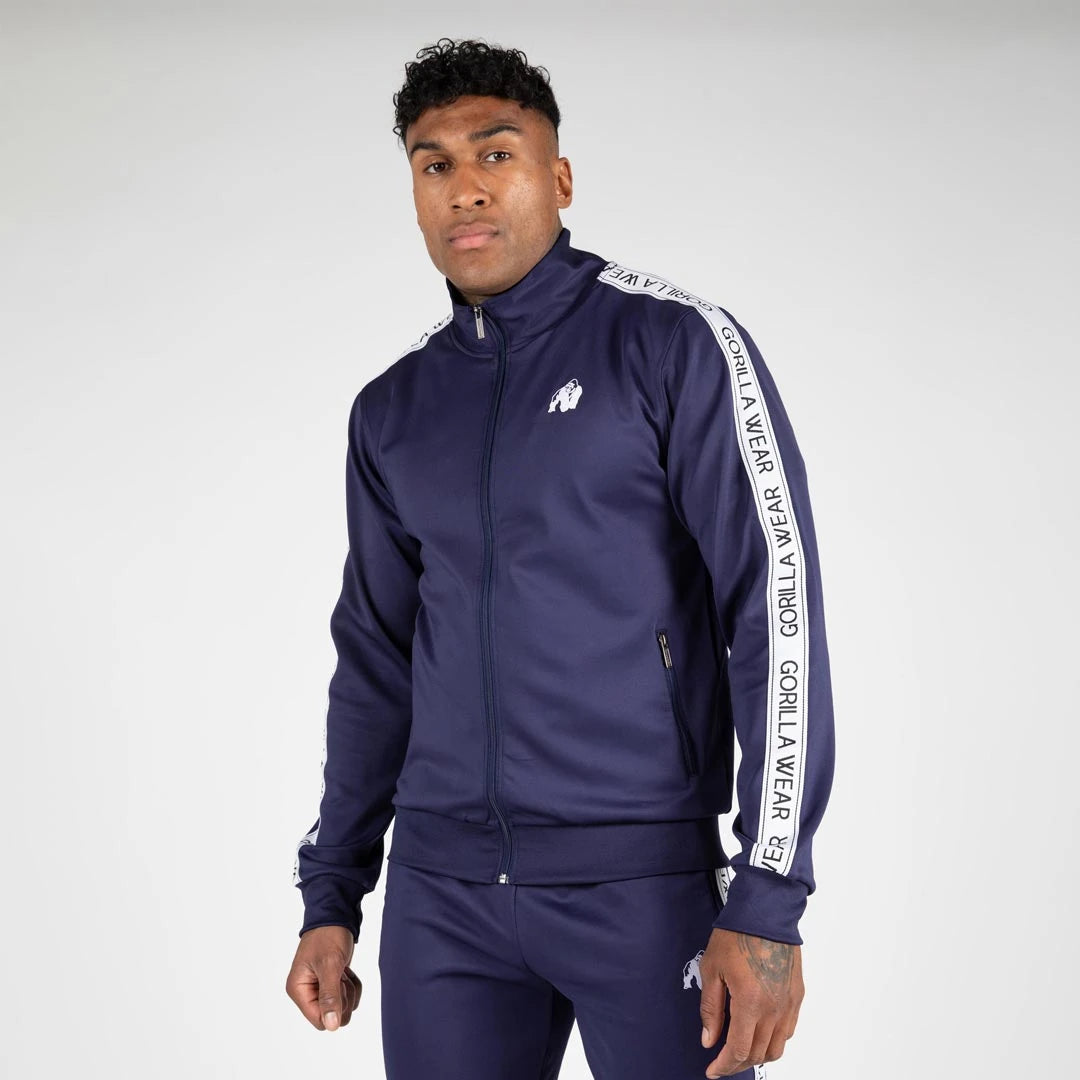 Man i marinblå Gorilla Wear Delaware Track Jacket navy, en sportig träningsjacka med vita revärer.