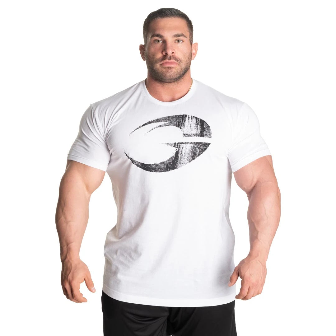 GASP Cadet Tee White, en vit t-shirt för herr med slitet svart logotryck, buren av en muskulös man.