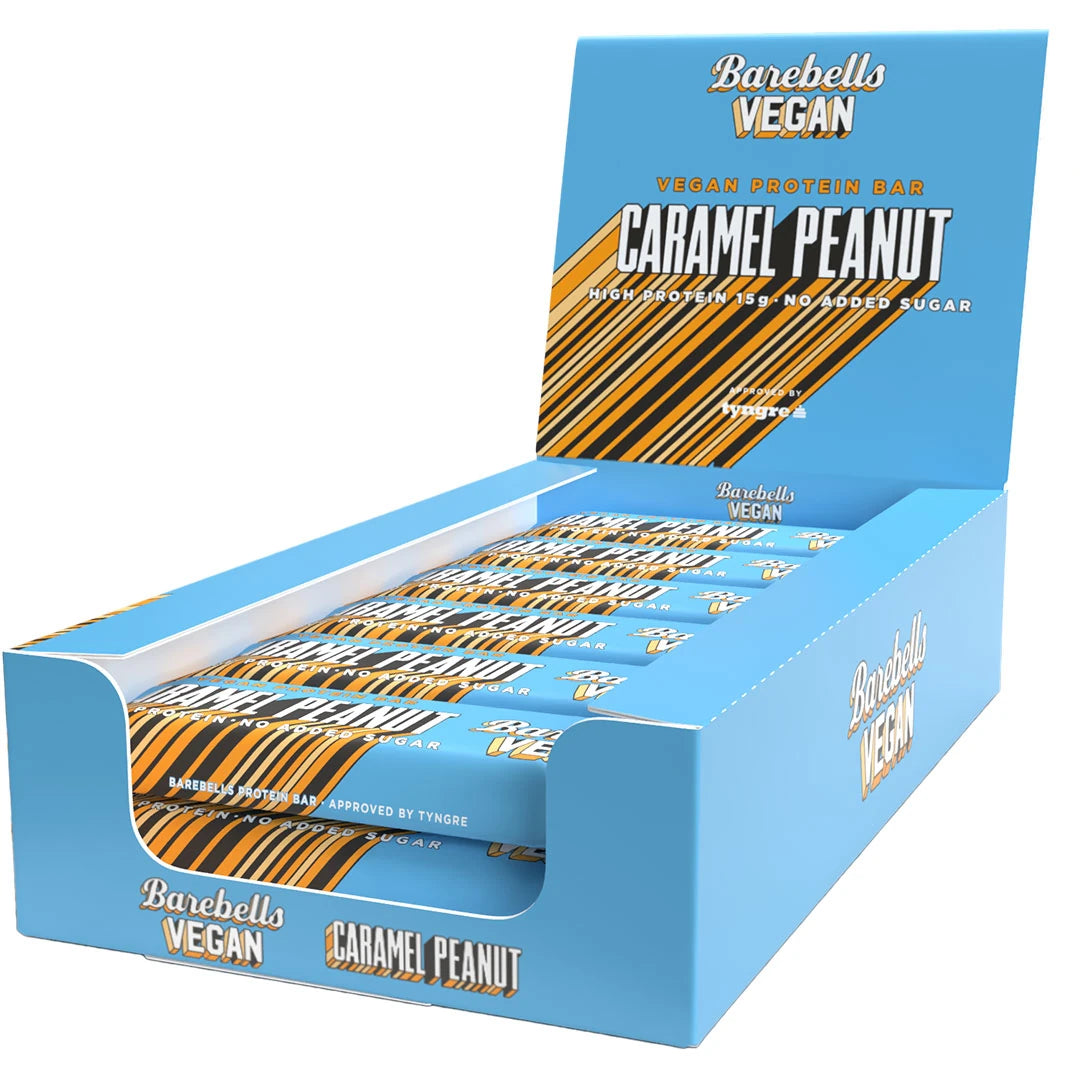 12 x Barebells Vegan Protein Bar 55 g Caramel Peanut i en ljusblå displaylåda med orange och bruna detaljer.