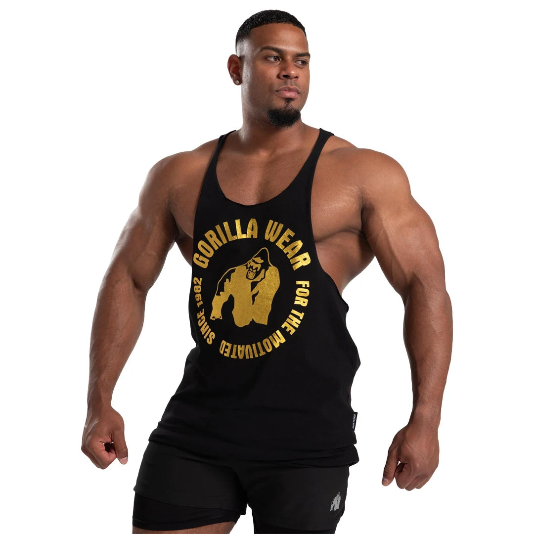 Gorilla Wear Melrose Stringer Black Gold, ett svart träningslinne med stort guldtryck buret av en muskulös man.
