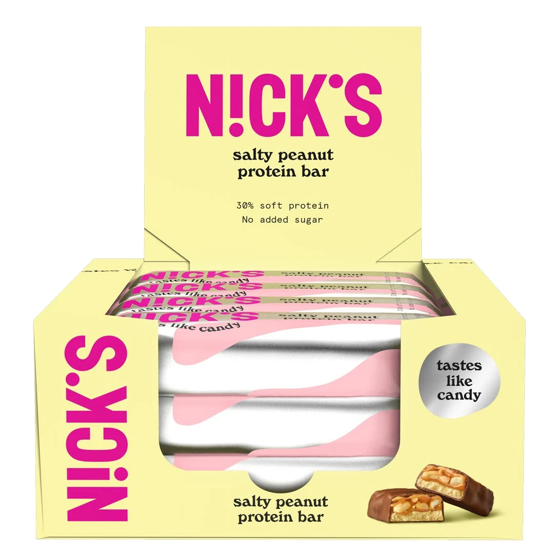 12 x NICKS Soft bar 50 g Salty Peanut i en öppen gul displaylåda som visar silvriga och rosa bars samt en delad bit.