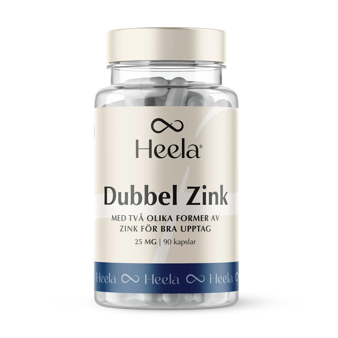 Heela Dubbel Zink 60 caps i en transparent burk med vita kapslar, beigefärgad etikett och blå bottenrand.