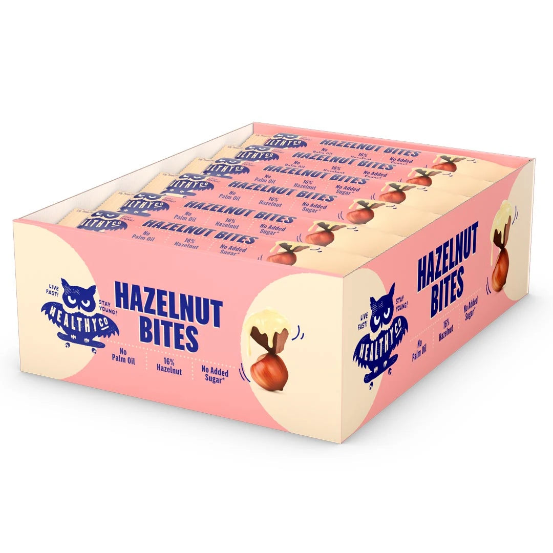 18 x HealthyCo Hazelnut Bites 21 g i en ljusgul och rosa displaylåda fylld med matchande chokladbitar., bild 1 av 1