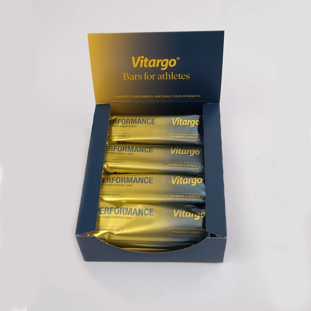 12 x Vitargo Performance Bar 55 g i en mörkblå låda fylld med guldiga energibars i smaken Rhubarb &amp; Vanilla., bild 1 av 1