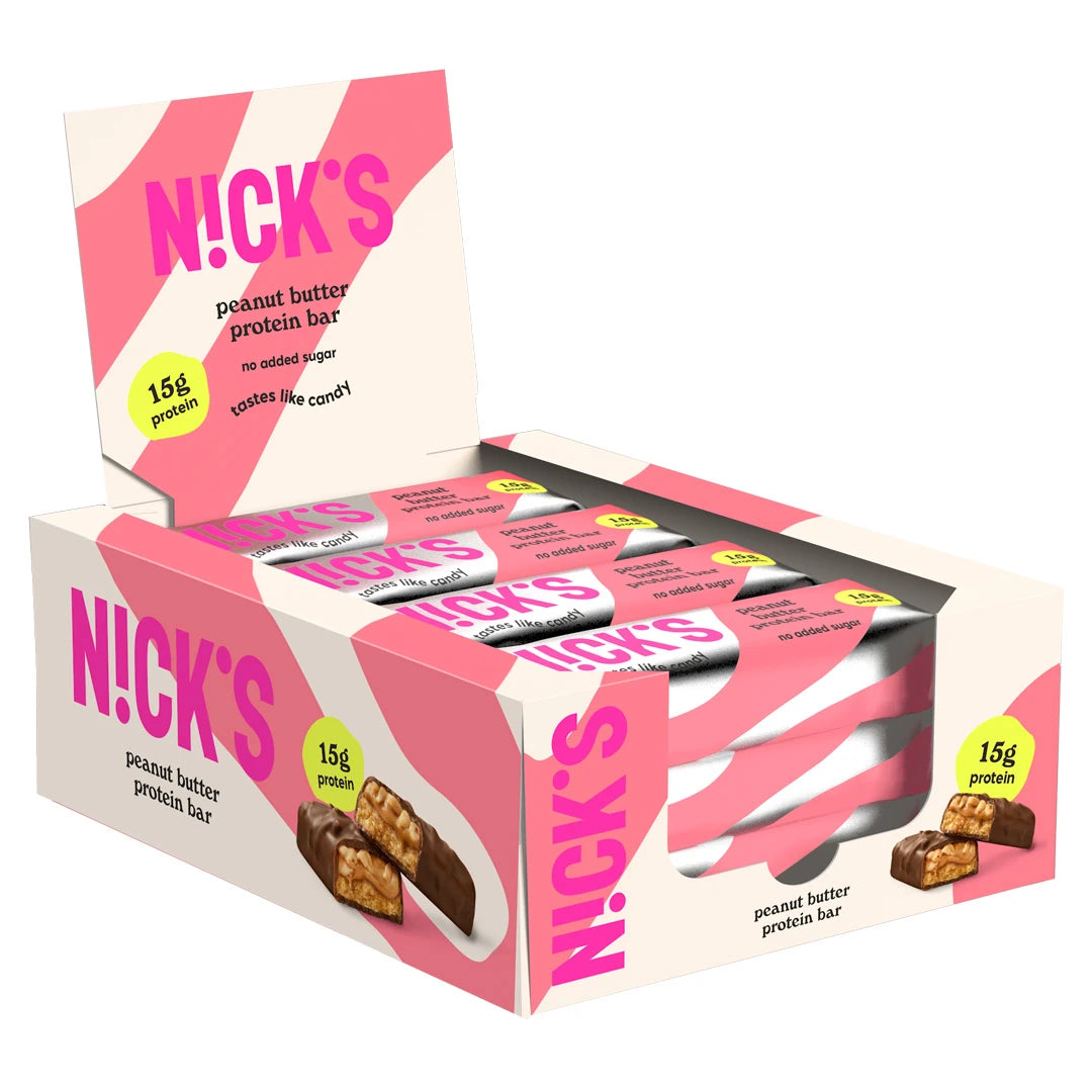 12 x NICKS Soft bar 50 g Peanut Butter i en rosa och vit kartong med matchande förpackningar inuti.