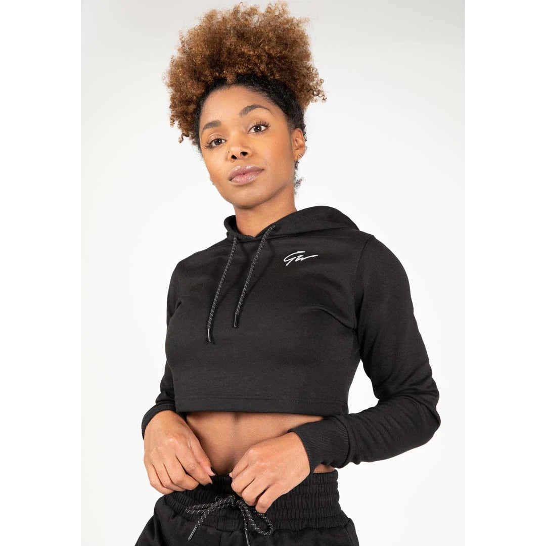 Gorilla Wear Pixley Crop Top Hoodie Black, en svart croppad huvtröja i slim fit med vit logga buren av en modell., bild 4 av 5