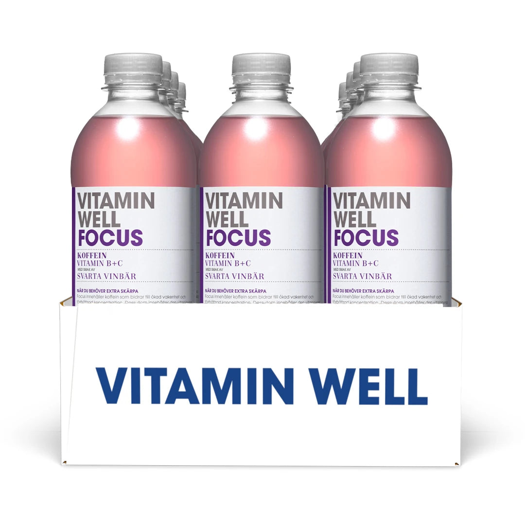 12 x Vitamin Well 500 ml Focus Svarta Vinbär i en vit kartong med klara plastflaskor, rosa dryck och lila detaljer.