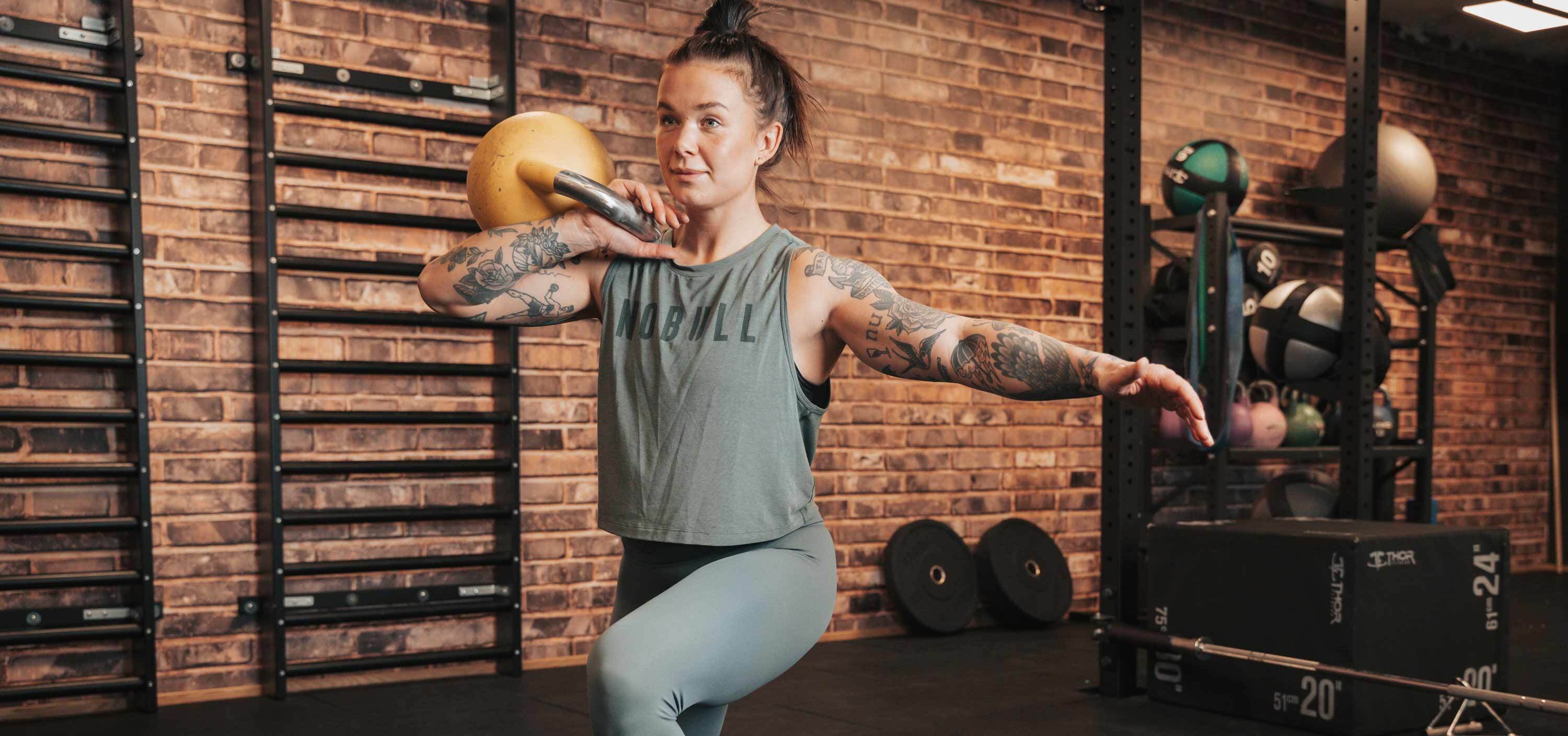 Hedda, personlig tränare, utför ett utfall med en kettlebell i gymmiljö. Bilden visar en del av det träningsprogram hon tagit fram för löpare som tränar inför ett halvmaraton.